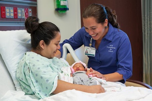 Promotora Violeta Audelo-Solano, right, comforts a new mom and baby during a bedside visit at NCH. 