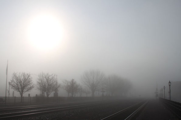 Sunrise in fog over railroad tracks