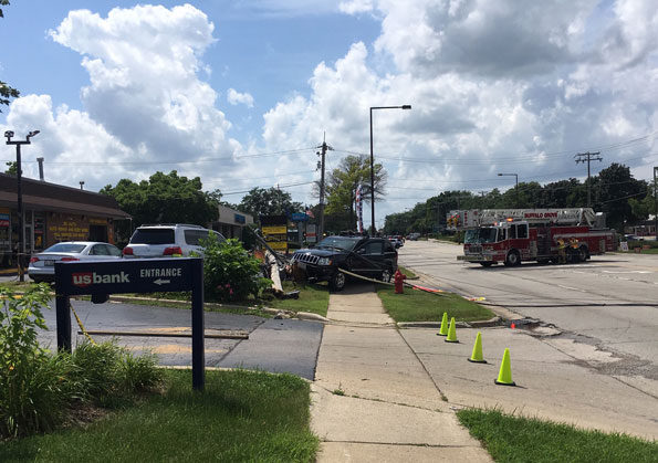 Jeep Grand Cherokee over sidewalk with broken utility pole and downed power lines