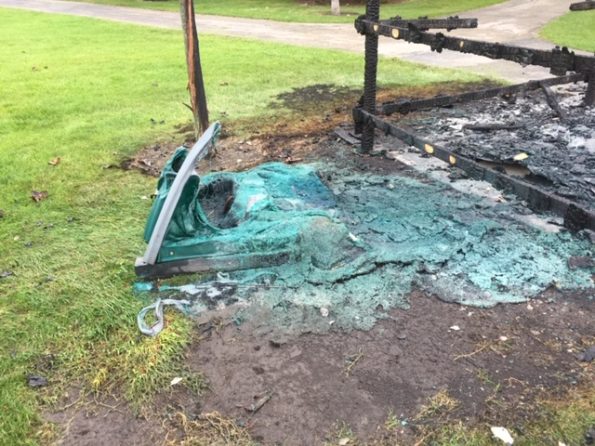 Fire-damaged portable toilet, enclosure and tree at Hasbrook Park on Maude Avenue