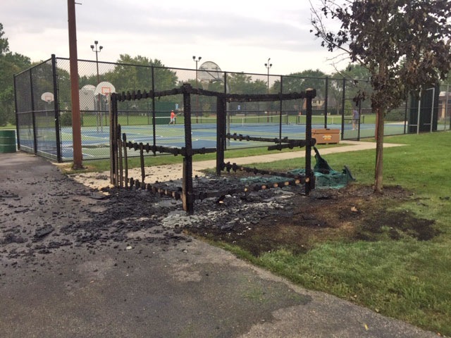 Fire-damaged portable toilet, enclosure and tree at Hasbrook Park on Maude Avenue