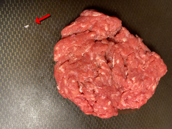 Foreign object picked out of ground sirloin and placed next to raw burger