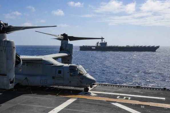 An MV-22B Osprey assigned to Marine Medium Tiltrotor Squadron Reinforced is secured to the flight deck of the amphibious assault ship USS America as the ship conducts an exercise in the Philippine Sea with the aircraft carrier USS Theodore Roosevelt, Feb. 15, 2020