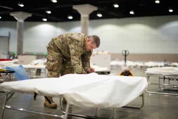 An airman with the California Air National Guard sets up a hospital bed in a medical station inside the Los Angeles Convention Center, March 29, 2020