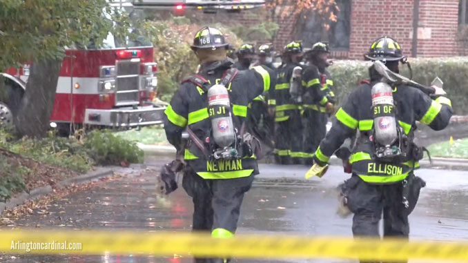 Firefighters with axes standing by t the scene of a gas main leak in Arlington Heights, Illinois