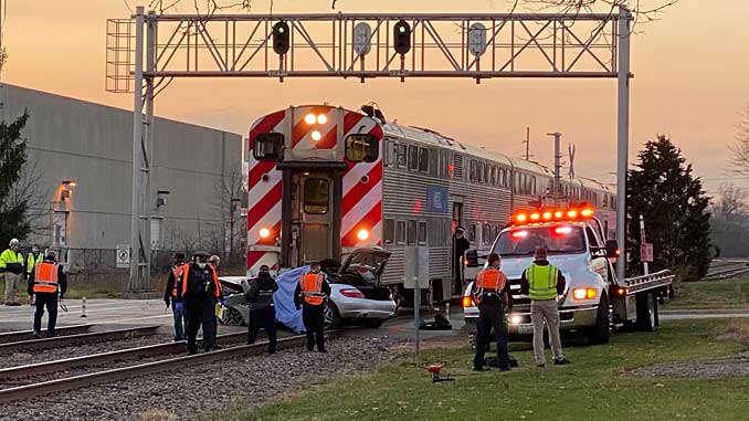 Preparing to tow silver Mercedes sedan off of railroad tracks at Ridge Avenue and Northwest Highway in Arlington Heights