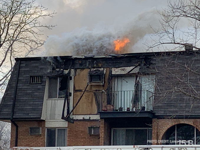 Fire showing from the roof after it burned off a section of vertical mansard roof at condo apartment fire in Palatine (PHOTO CREDIT: Lance Neuses)