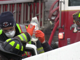 Firefighter/paramedics holding an IV bag during extrication of a crash victim from a severely-damaged vehicle on Algonquin Road just west of New Wilke Road near the border of Arlington Heights and Rolling Meadows