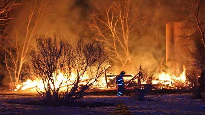 Firefighter walks across property in front of burning barn on Kazmer Road in Newport Township (SOURCE: Newport Township Fire Protection District)