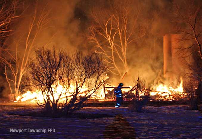 Firefighter walks across property in front of burning barn on Kazmer Road in Newport Township (SOURCE: Newport Township Fire Protection District)