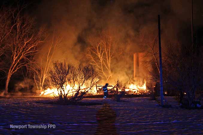 Firefighter walks across property in front of burning barn on Kazmer Road in Newport Township (SOURCE: Newport Township Fire Protection District)