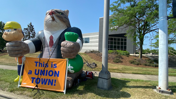 Inflatable "Fat Cat" holding a laborer by the neck with a sign that says, "This is a Union Town!" with Local One participants at the southwest corner of Palatine Road and Rand Road in Arlington Heights