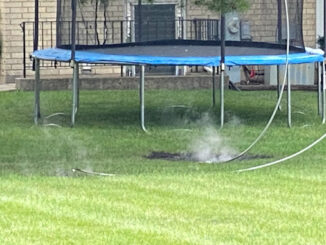 Power line down near a backyard trampoline showing smoke after arcing and burning the lawn on Walnut Avenue south of Olive Street in Arlington Heights