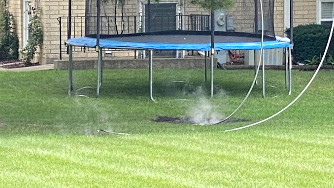 Power line down near a backyard trampoline showing smoke after arcing and burning the lawn on Walnut Avenue south of Olive Street in Arlington Heights