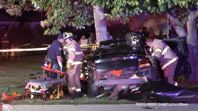 View toward the rear end of a Dodge Charger at a fatal crash scene shows firefighters working to free occupants of the Dodge Charger that hit a utility pole on Dugdale Road in Waukegan on Saturday, July 24, 2021