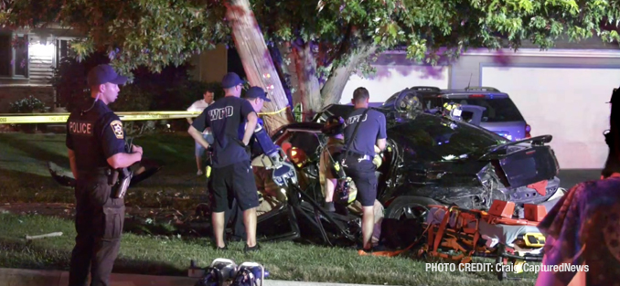 Fatal crash scene shows Dodge Charger stopped by a utility pole near residences and personal vehicles