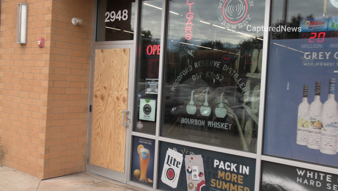 Front glass door boarded up at Esplanade Wine & Spirits on West Euclid Avenue near Salt Creek Lane in Arlington Heights