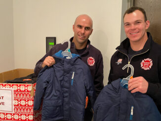 Firefighters at Arlington Heights Fire Station 2 show off some coats already donated to the box at the lobby at Fire Station 2.