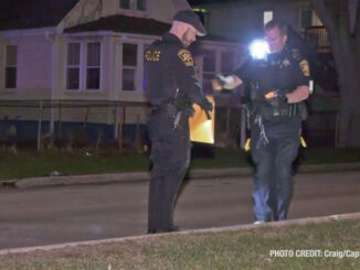 Police handoff evidence collected on the street -- one police officer hands off to another police officer holding an evidence envelope (Craig/CapturedNews)