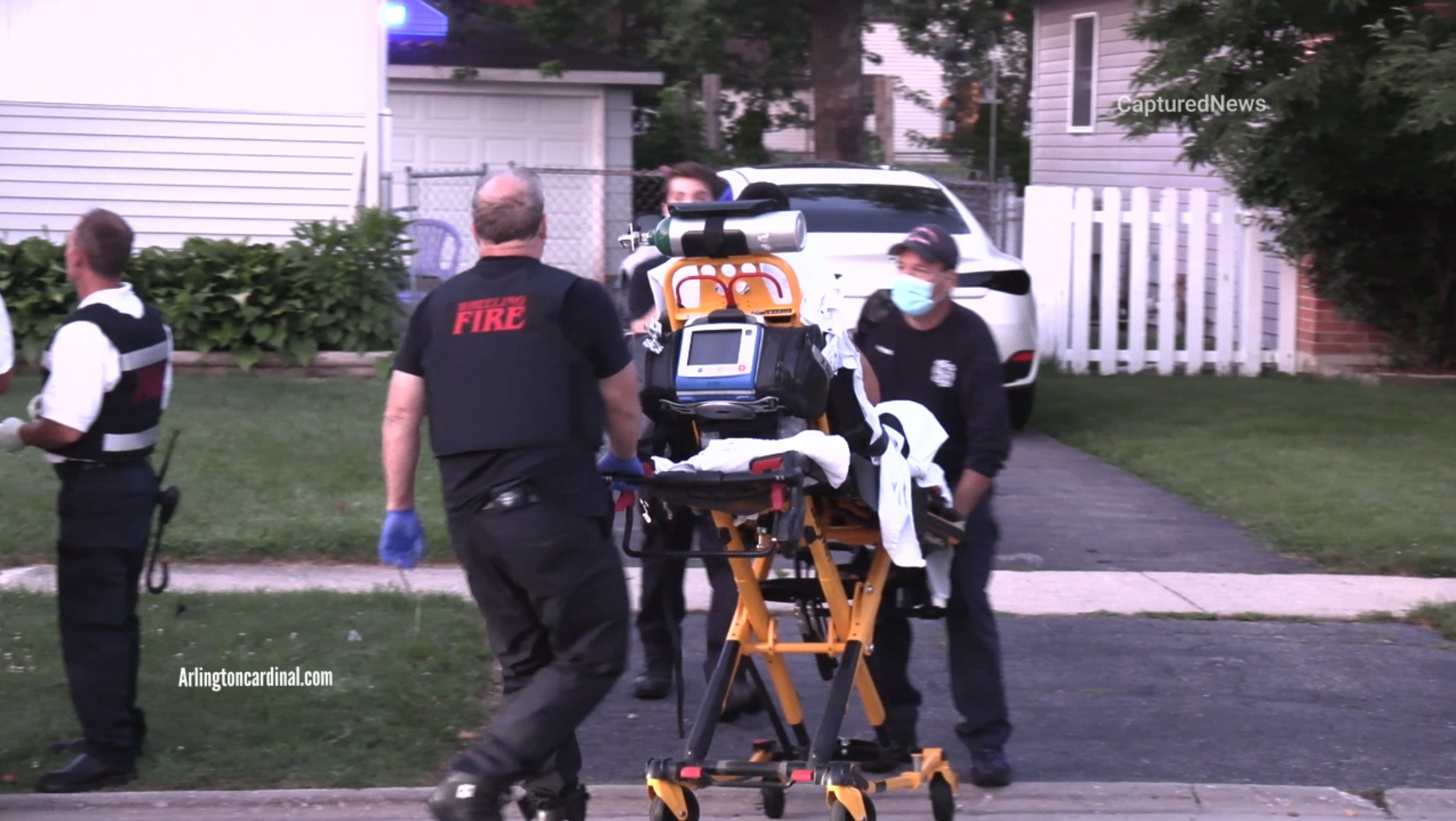 Paramedics moving a patient to the ambulance from a shooting scene on Fletcher Drive west of Elmhurst Road on Saturday, July 30, 2022