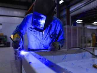 Welder working in a warehouse casting a blue hue
