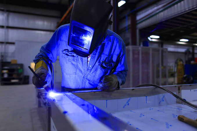 Welder working in a warehouse casting a blue hue