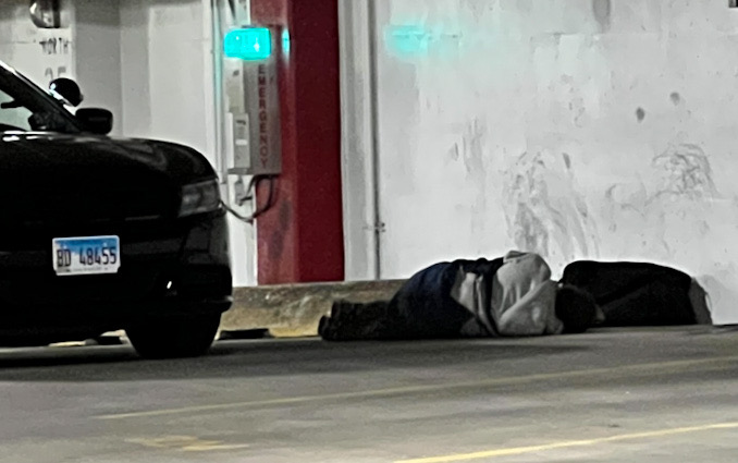 Police helping a man down in the underground parking garage under Arlington Town Square in the block of 0-99 South Evergreen Avenue in Arlington Heights on Sunday, December 4, 2022