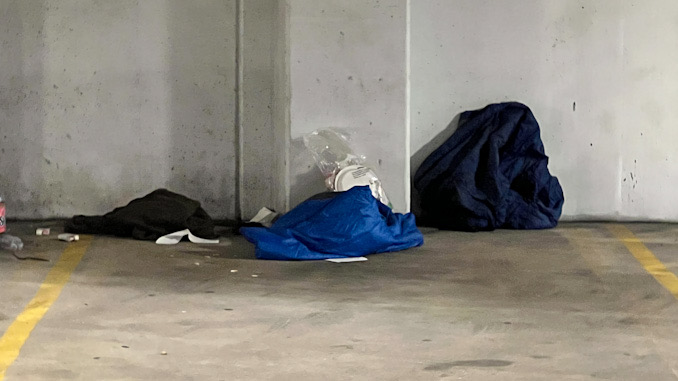 Police helping a man down in the underground parking garage under Arlington Town Square in the block of 0-99 South Evergreen Avenue in Arlington Heights on Sunday, December 4, 2022