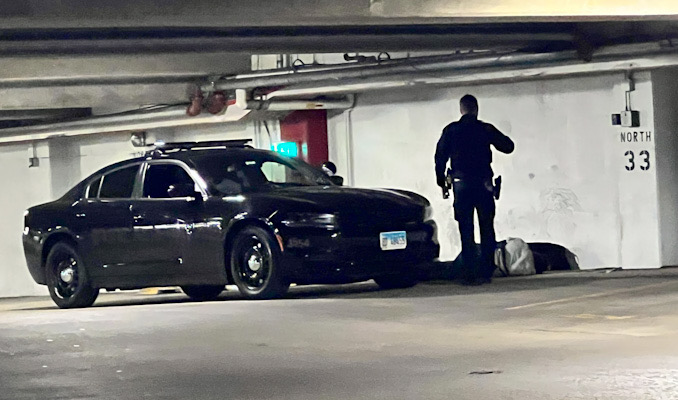 Police helping a man down in the underground parking garage under Arlington Town Square in the block of 0-99 South Evergreen Avenue in Arlington Heights on Sunday, December 4, 2022