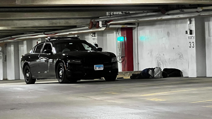 Police helping a man down in the underground parking garage under Arlington Town Square in the block of 0-99 South Evergreen Avenue in Arlington Heights on Sunday, December 4, 2022