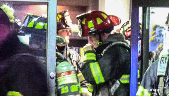 A fire lieutenant communicates on a portable radio while in the lobby coordinating fire operations.