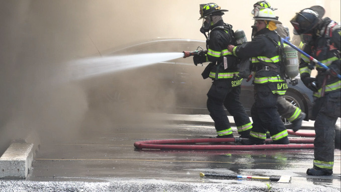 Firefighters direct a stream of water into the front of a store in a strip mall at the southeast corner of Elmhurst Road and Hintz Road in Prospect Heights (CARDINAL NEWS)