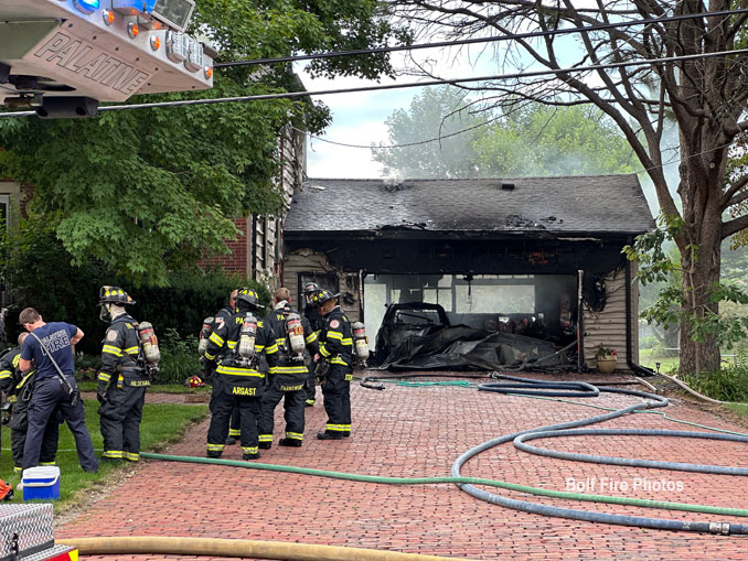 Firefighters changing air bottles in front of a garage where a car was destroyed on Wednesday, July 19, 2023 (PHOTO CREDIT: Jimmy Bolf)