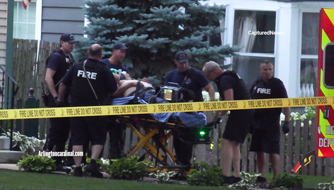 Paramedics transfer an adult male from inside  the house to an ambulance parked on Campbell Street on Saturday, August 5, 2023.