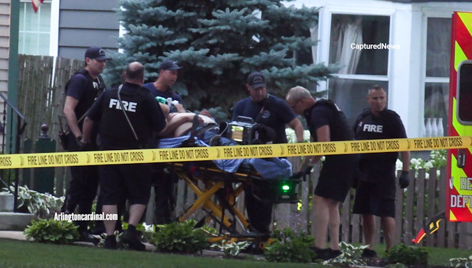 Paramedics transfer an adult male from inside the house to an ambulance parked on Campbell Street on Saturday, August 5, 2023.