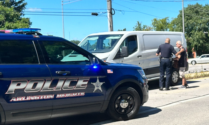 An Arlington Heights police officer consoles the driver of the white van immediately after the crash at US-12 (Rand Road) and Wilke Road in Arlington Heights on Saturday morning, August 12, 2023