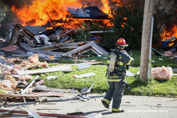 House burning while a fire lieutenant assesses for 
hazards after a home was leveled by an apparent natural gas explosion on Monday, October 9, 2023 (SOURCE: Woodstock Fire/Rescue District)