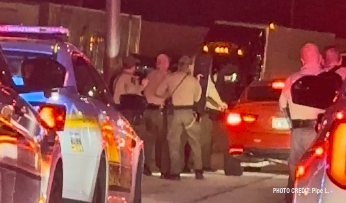 A witness snapped a photo as police carrying body shields approached the suspect's red vehicle, and as the photographer was stopped in traffic directly behind marked Cook County Sheriff's vehicles and Illinois State Police vehicles (PHOTO CREDIT: Pipe L.)