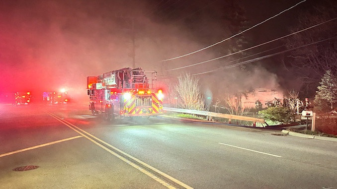 Smoke blows from east to west across Hicks Road while a fire destroyed a vacant house Thursday night March 21, 2024 at 1855 North Hicks Road in Palatine.
