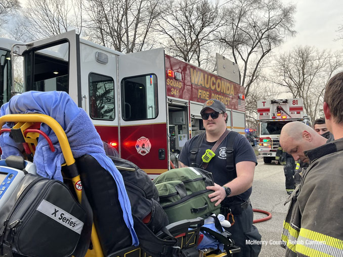 A paramedic with Barrington-Countryside Fire Protection District rolls an ambulance gurney with Advanced Life Support equipment past the fire scene in unincorporated Crystal Lake  on Friday, March 29, 2024 (SOURCE: McHenry County Rehab Canteen)