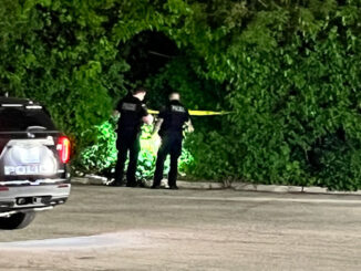 Mount Prospect police officers investigating an opening in shrubs at a rear parking lot west of "Fry the Coop" that leads to and from an apartment complex on Blossom Lane west of the restaurant (CARDINAL NEWS)