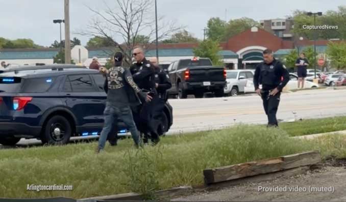 A male adult in motorcycle attire was pushed back by police after he was asked to leave the hot zone/threat zone at the crash scene while one of the vehicles was burning (provide from cellphone video)