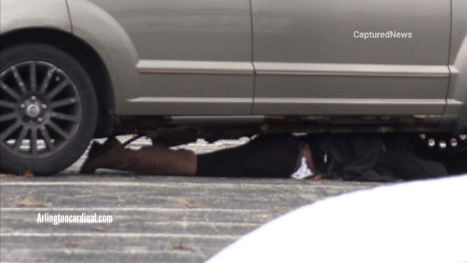 A woman facedown underneath her vehicle in a standoff with Metra and Arlington Heights police at the Arlington Park Metra Station parking lot Sunday morning, November 9, 2025 (CARDINAL NEWS)